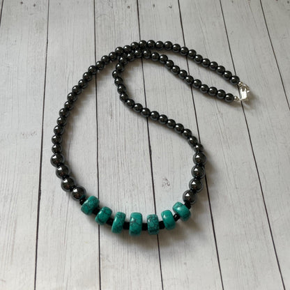 Necklace with black and turquoise beads on a wooden surface
