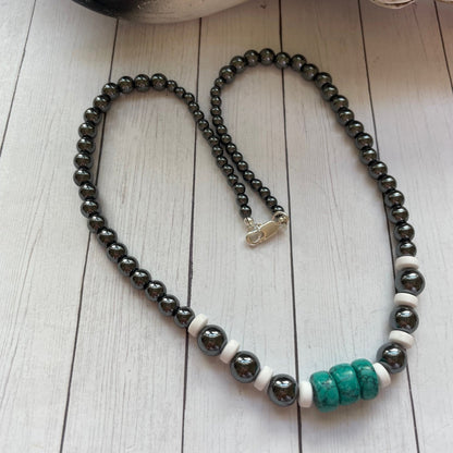 Necklace with black, white, and turquoise beads on a wooden surface