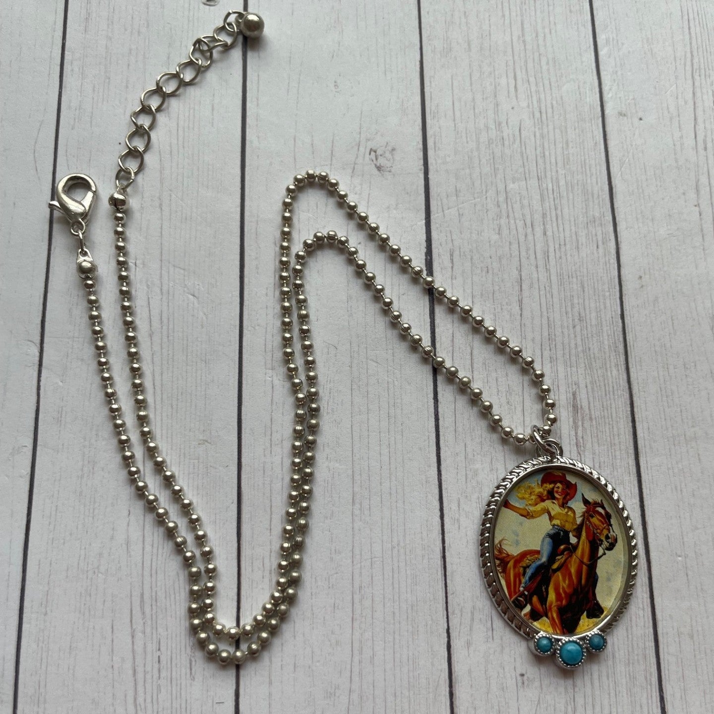 Necklace with a colorful horse and rider pendant on a wooden surface