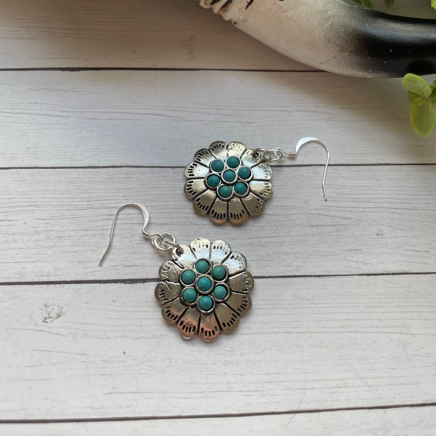 Silver earrings with turquoise stones on a wooden surface