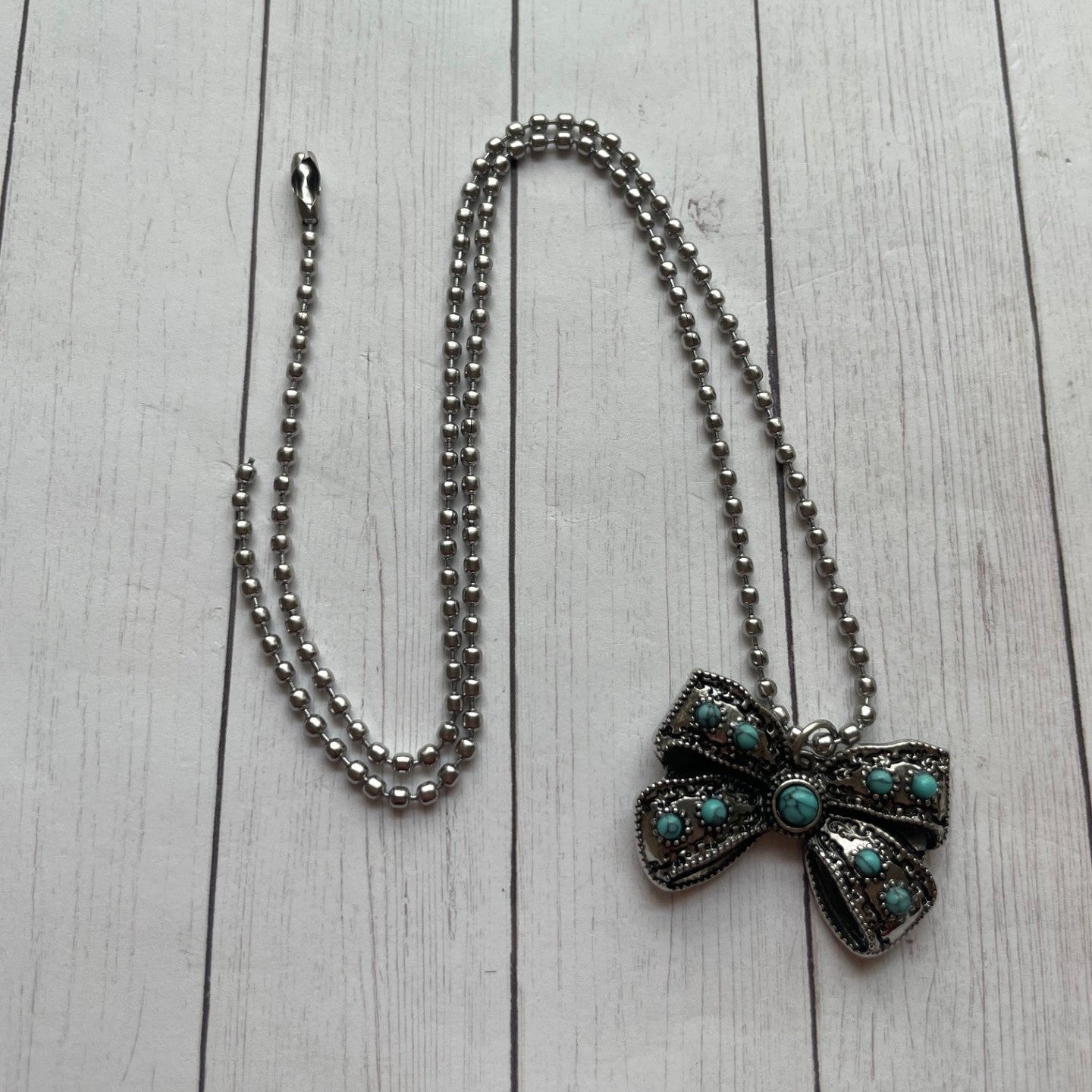 Necklace with a bow-shaped pendant on a light wooden surface