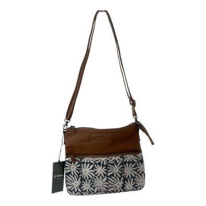 A women's crossbody handbag with a brown leather top and a navy blue and white floral patterned bottom half, featuring a long shoulder strap and a hanging black brand tag.