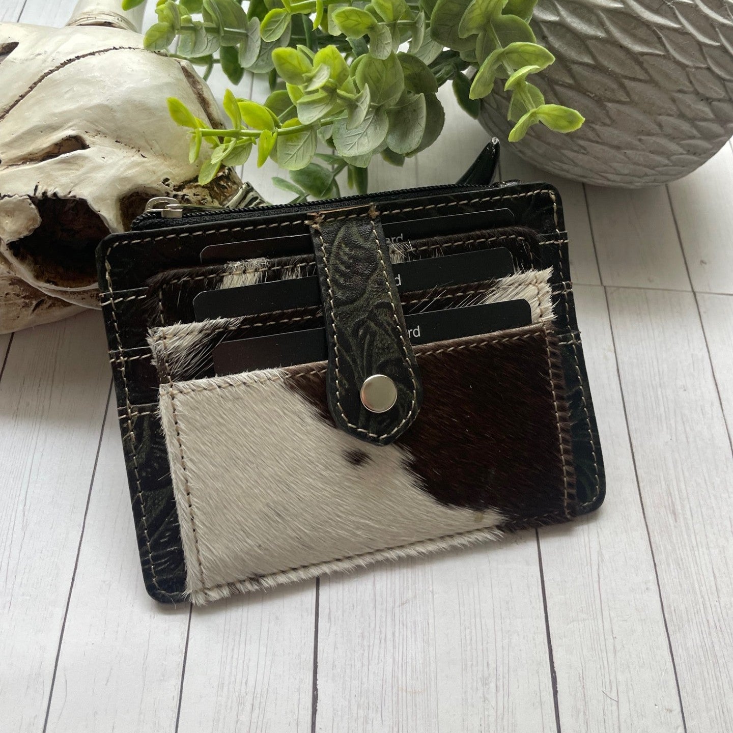 Black and white cowhide and leather wallet with a snap closure and credit card slots