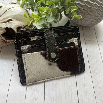 Black and white cowhide and leather wallet with a snap closure and credit card slots