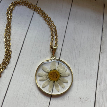 Necklace with a pendant featuring a pressed flower on a wooden surface