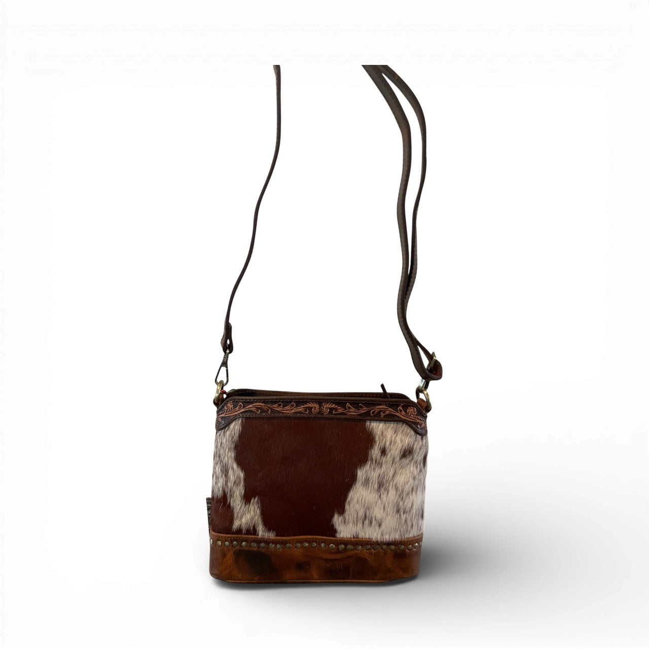 Brown and white cowhide leather bag with a strap on a white background