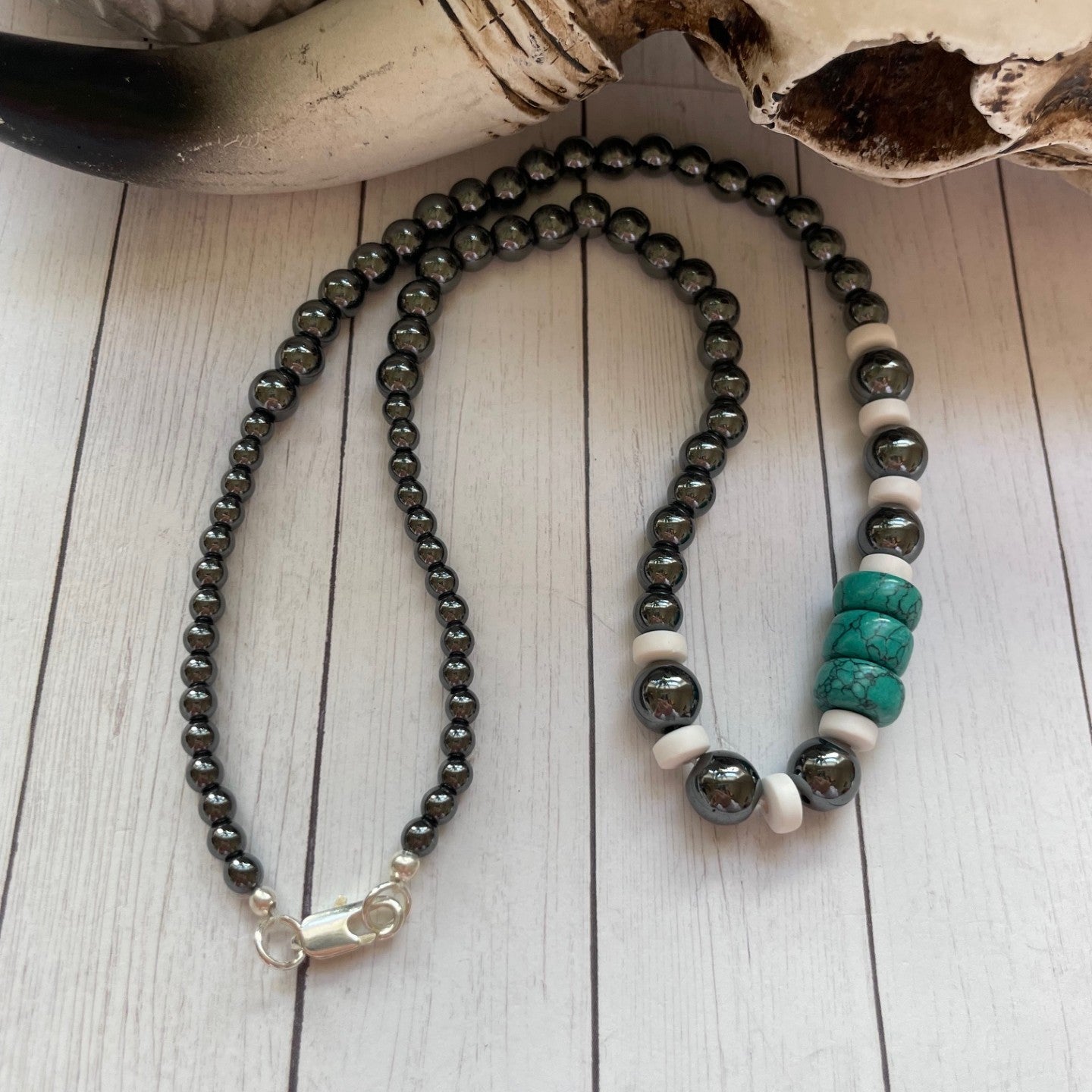 Beaded necklace with black, white, and turquoise beads on a wooden surface