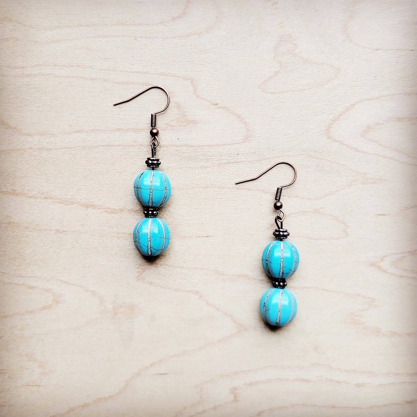 Pair of turquoise beaded earrings on a light wood surface