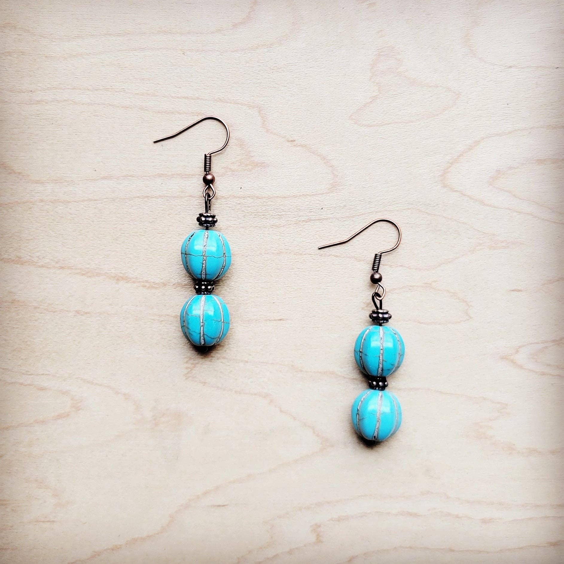 Pair of turquoise beaded earrings on a light wood surface