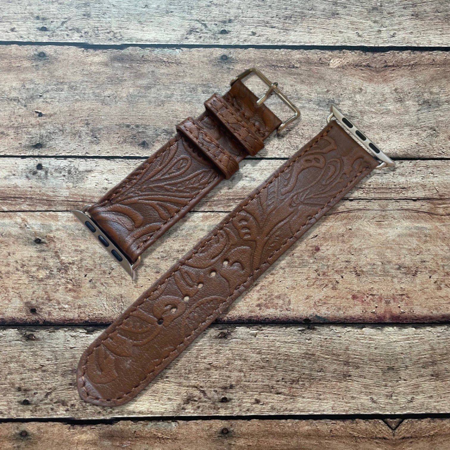 Brown leather watch strap with embossed design on a wooden surface