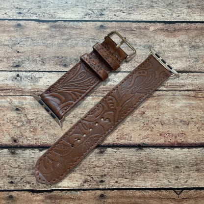 Brown leather watch strap with embossed design on a wooden surface