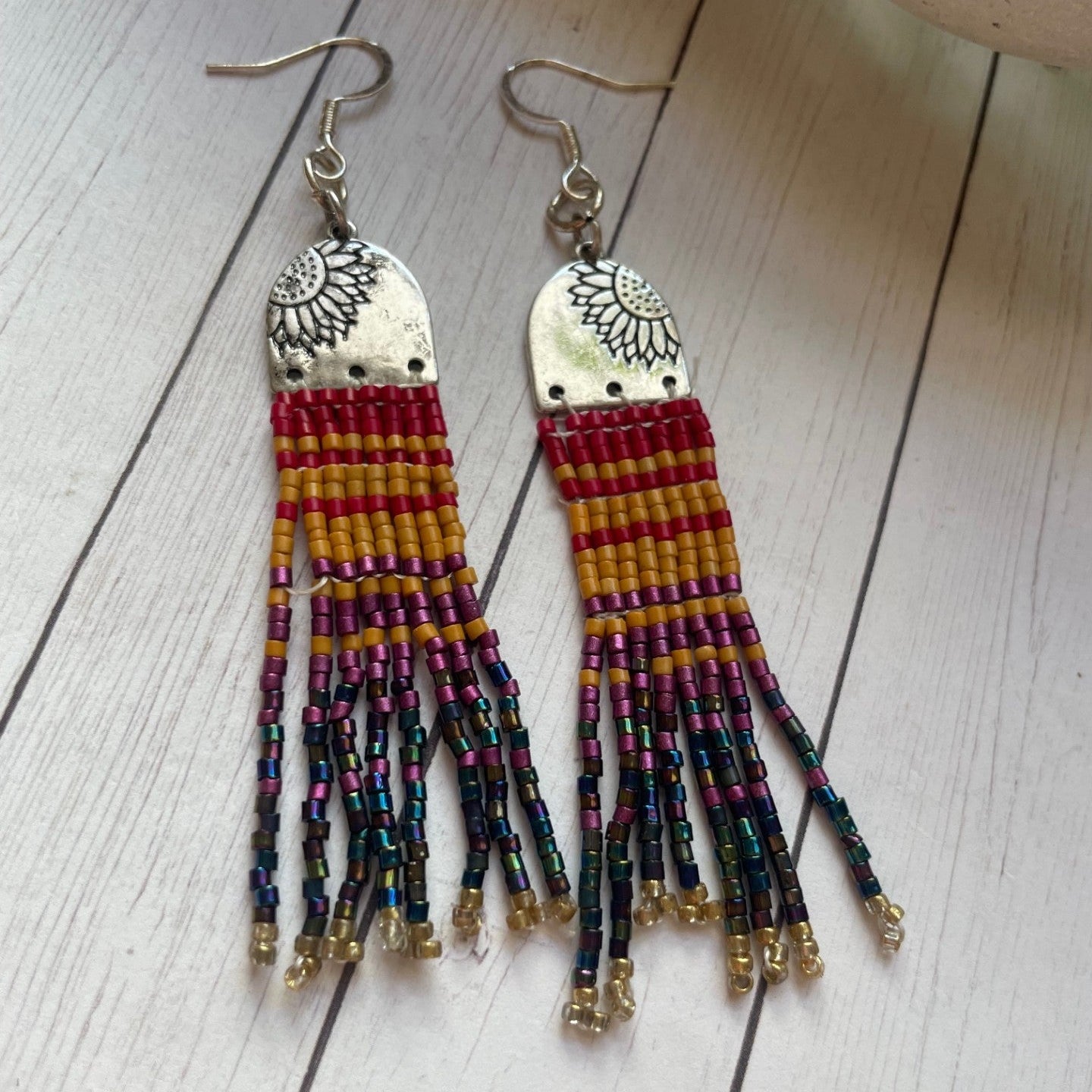 Beaded earrings with colorful fringes on a wooden surface