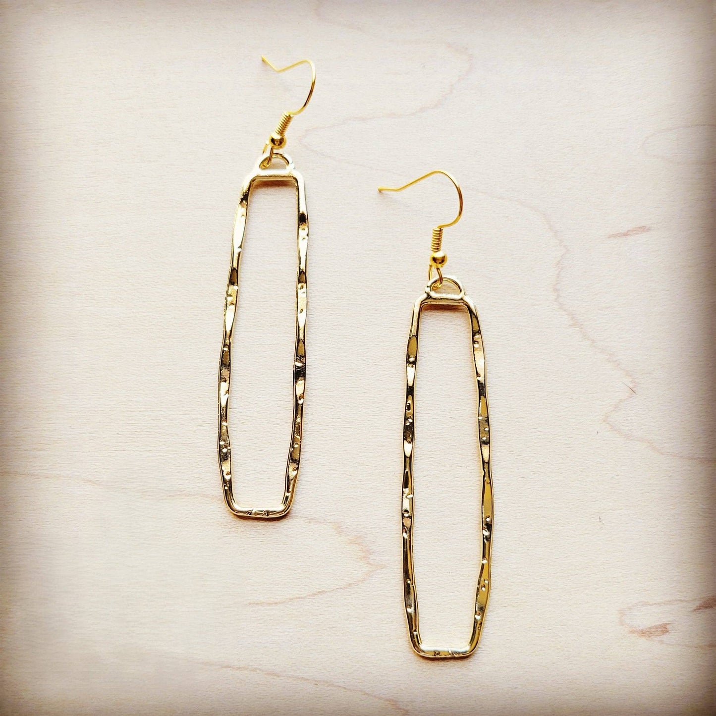 Gold hoop earrings on a light marble background