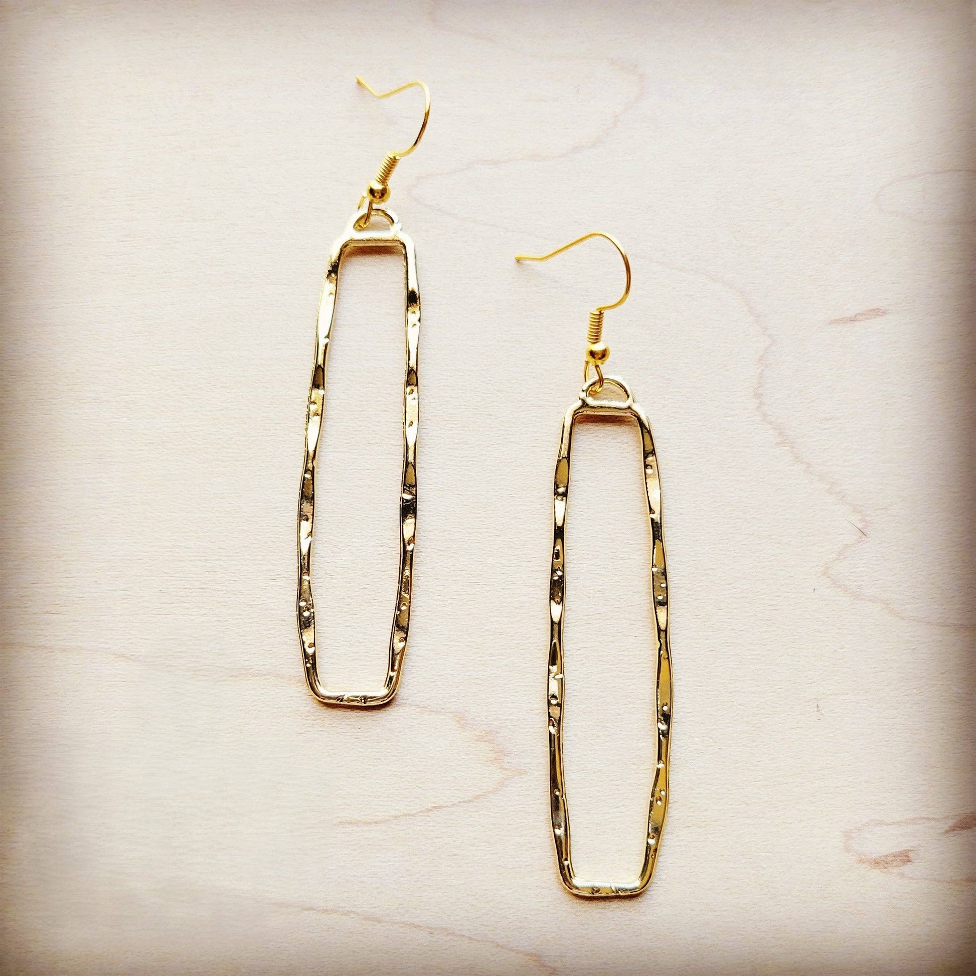 Gold hoop earrings on a light marble background