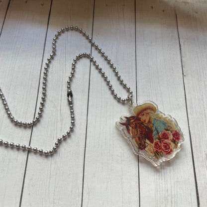 Necklace with a pendant featuring a horse and floral design on a wooden surface