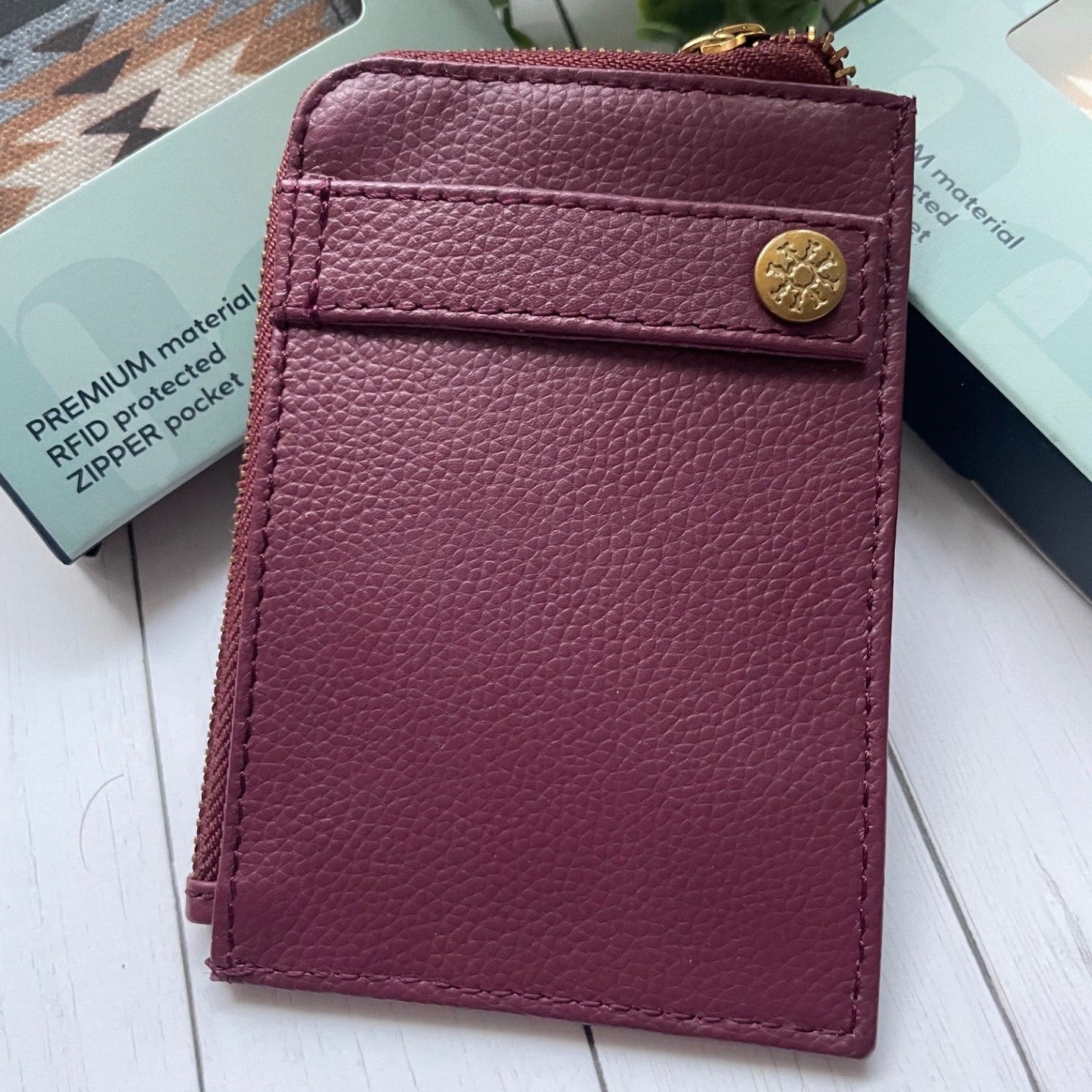 Purple leather wallet with gold button on a white surface
