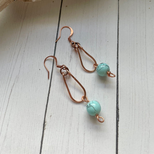 Copper Loop with a Turquoise colored bead hanging from copper colored earrings