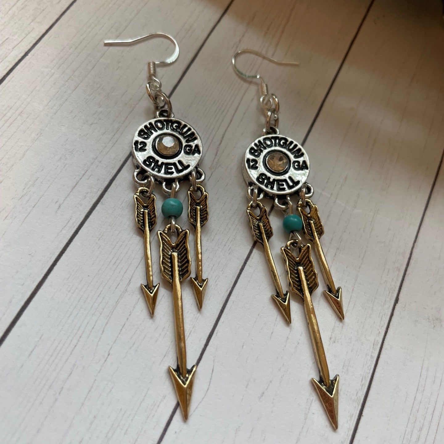 Pair of earrings with arrow designs on a wooden surface