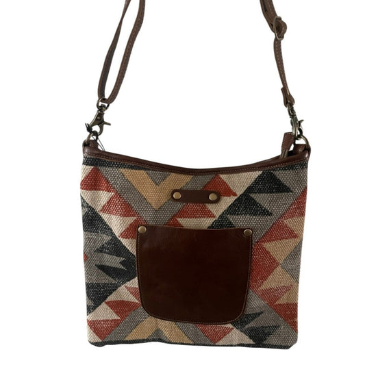 Crossbody bag with geometric pattern and brown leather pocket on a white background