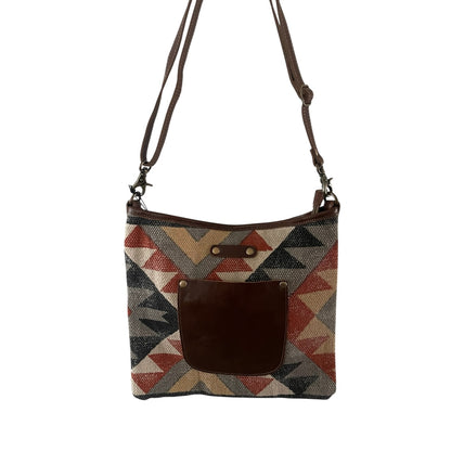Crossbody bag with geometric pattern and brown leather pocket on a white background