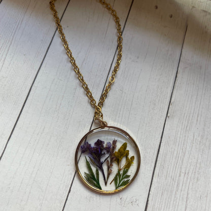 Necklace with a round pendant featuring pressed flowers on a wooden surface