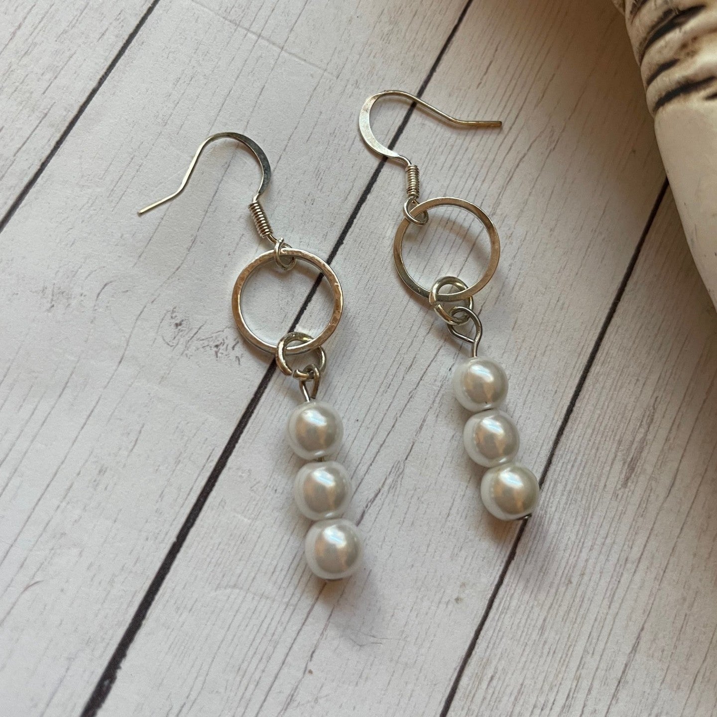 Pair of pearl drop earrings on a wooden surface