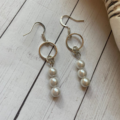 Pair of pearl drop earrings on a wooden surface