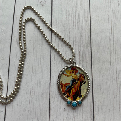 Necklace with a pendant featuring a horse and rider on a wooden surface