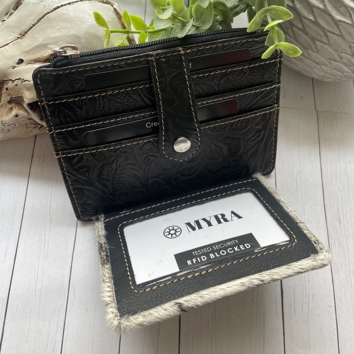 Black and white cowhide and leather wallet with a snap closure and credit card slots