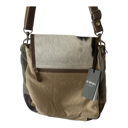 A crossbody shoulder bag featuring a cowhide-patterned flap, a beige canvas body, dark brown leather trim, and a hanging MWRA brand tag, shown against a plain white background.