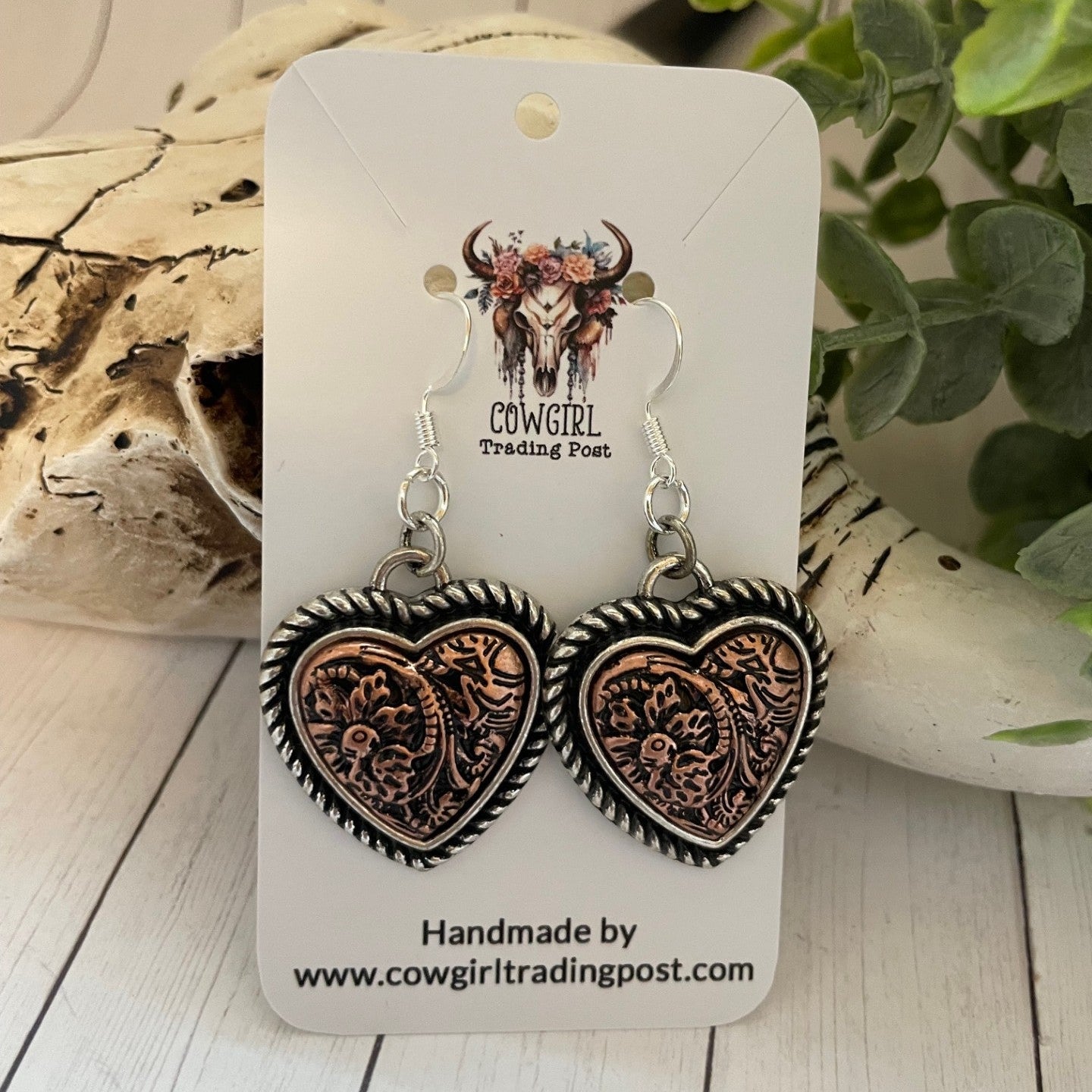 Heart-shaped earrings on a Cowgirl Trading Post card with decorative background