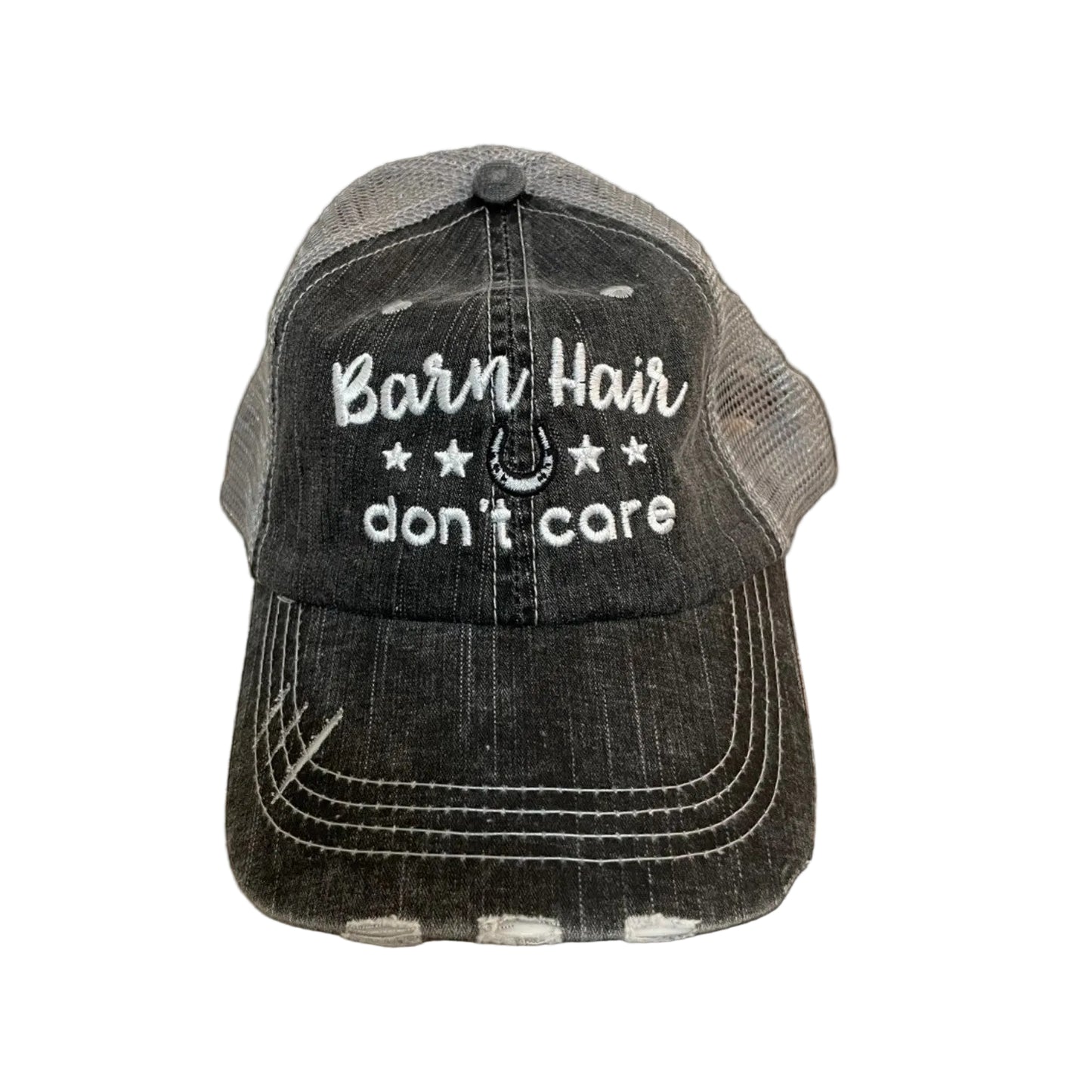 Black and gray cap with 'Barn Hair don't care' text on a wooden surface with hay bales in the background