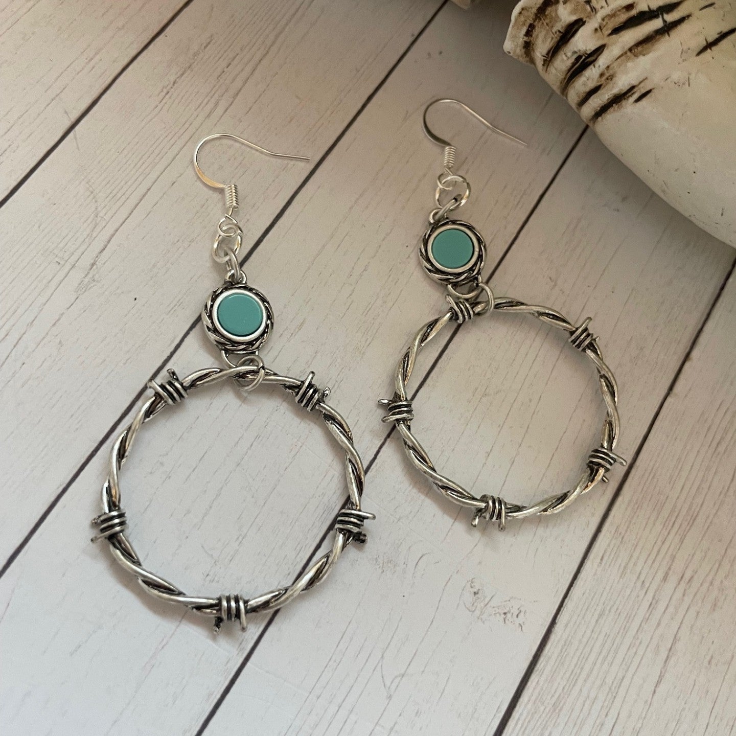Silver hoop earrings with turquoise stones on a wooden surface