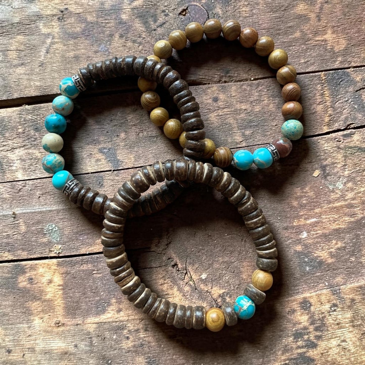 Three beaded bracelets with turquoise and brown beads on a wooden surface