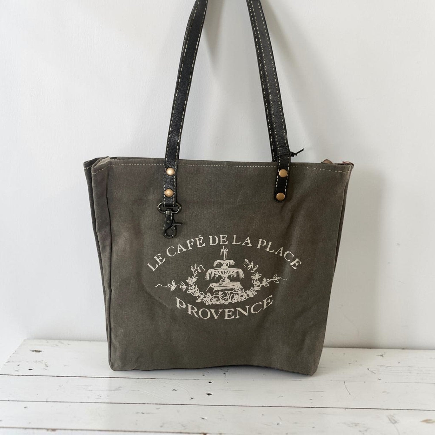 Gray tote bag with 'Le Cafe de la Place Provence' logo on a white background