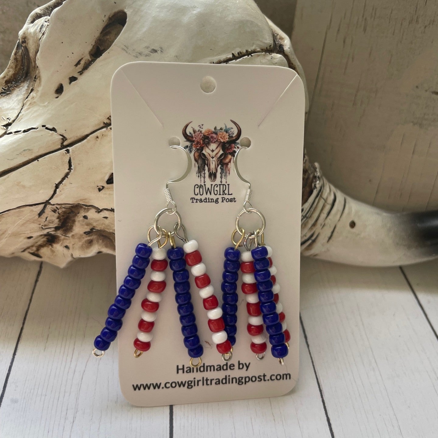 Beaded earrings on a Cowgirl Trading Post card with driftwood in the background