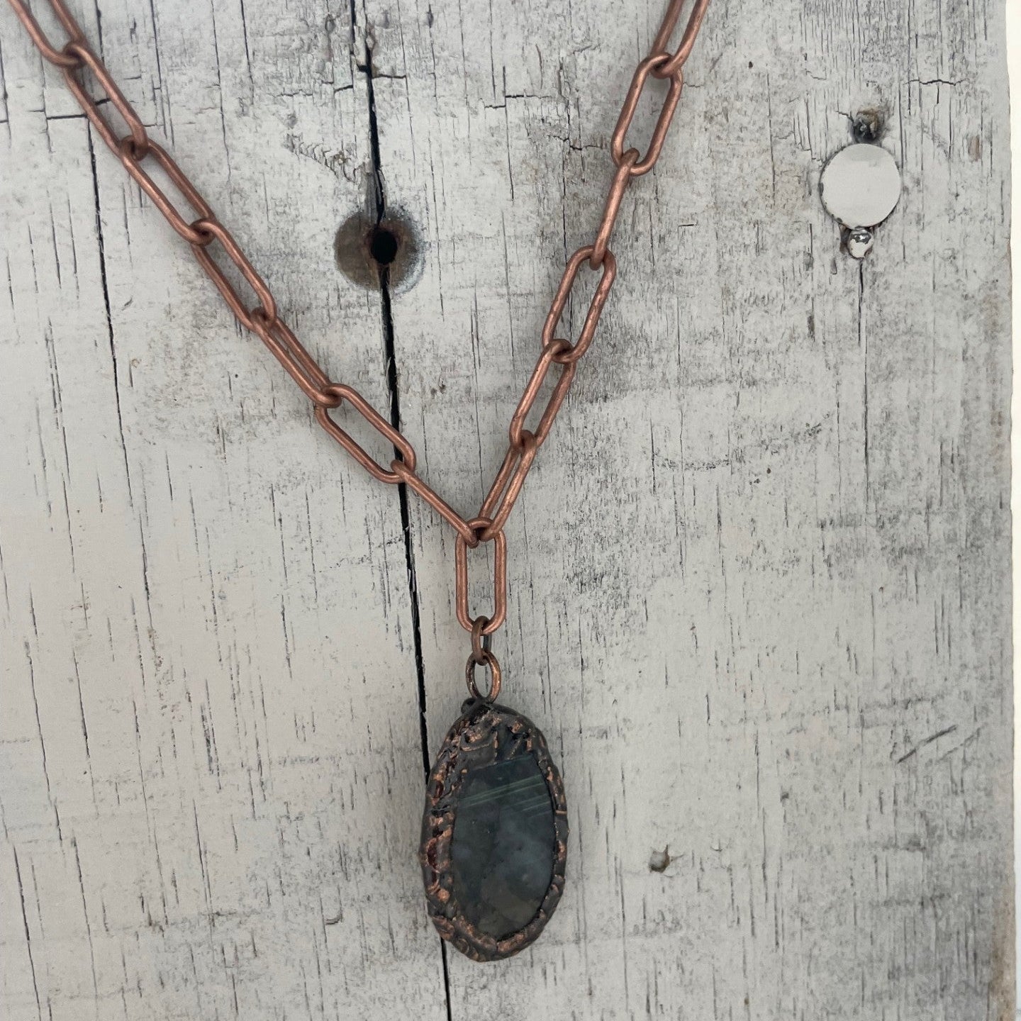 Necklace with a dark pendant on a textured white surface