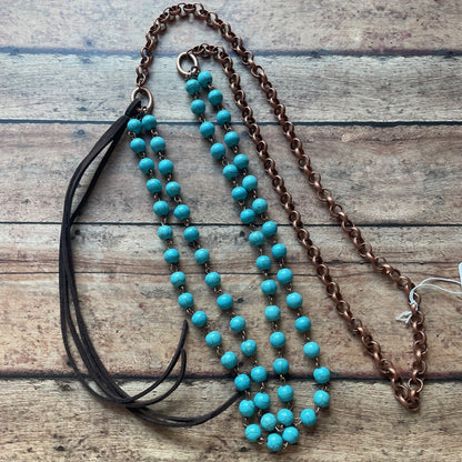 Turquoise beaded necklace with a brown chain on a wooden surface