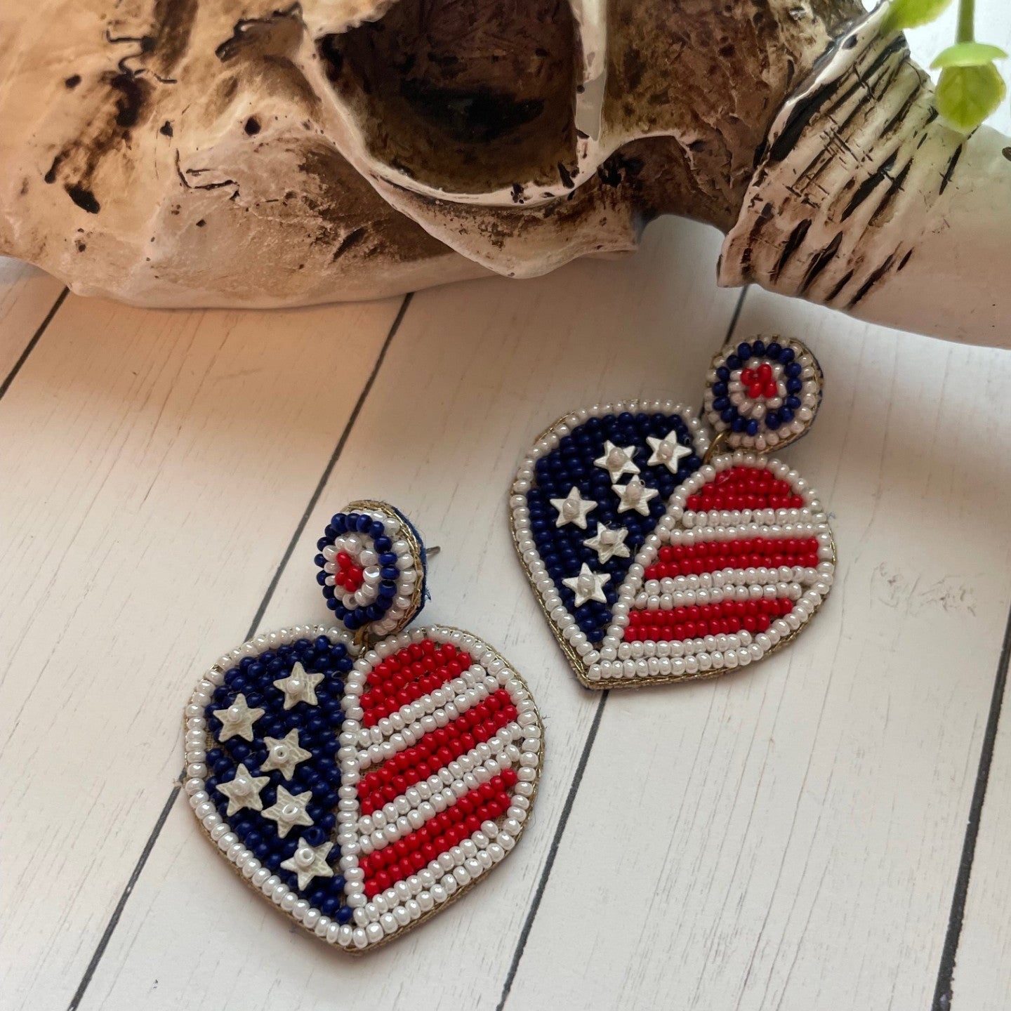 Heart-shaped earrings with American flag design on a wooden surface