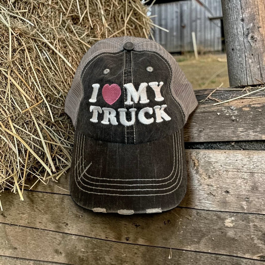 Cap with 'I ❤️ MY TRUCK' text on a wooden surface with hay in the background