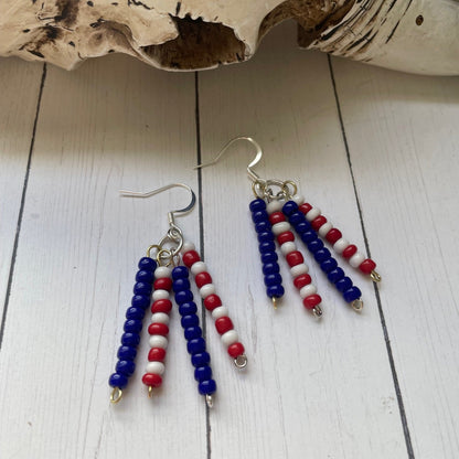 Pair of beaded earrings with red, white, and blue beads on a wooden surface.