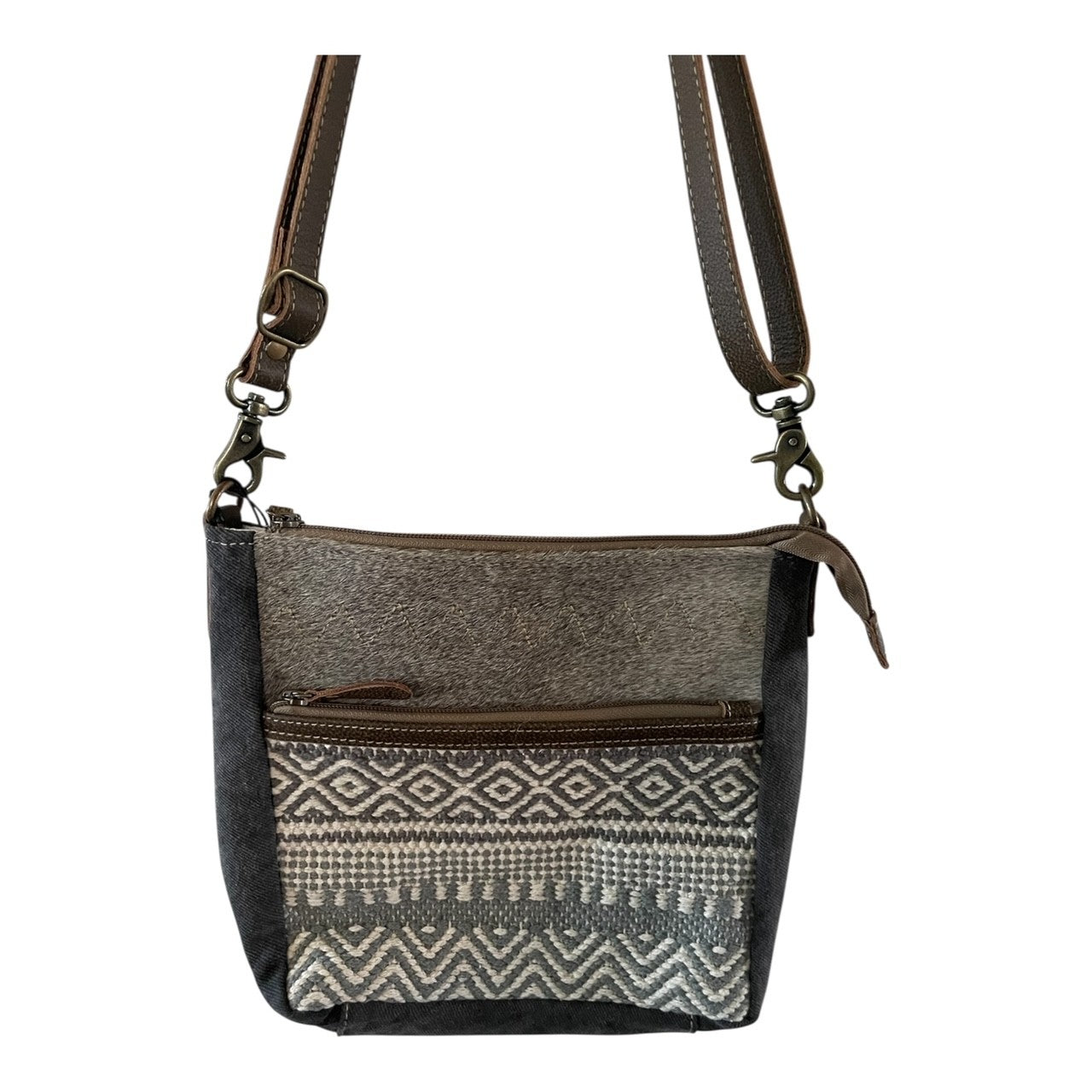 Crossbody bag with patterned flap and brown strap on a white background