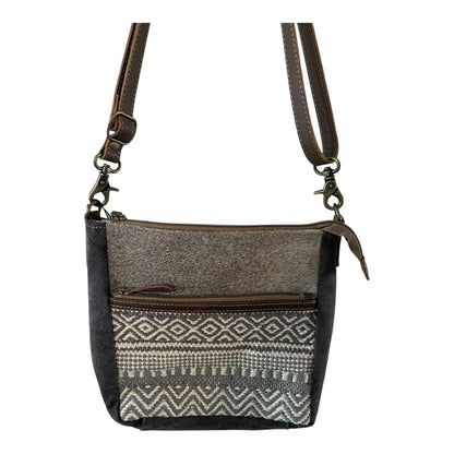 Crossbody bag with patterned flap and brown strap on a white background