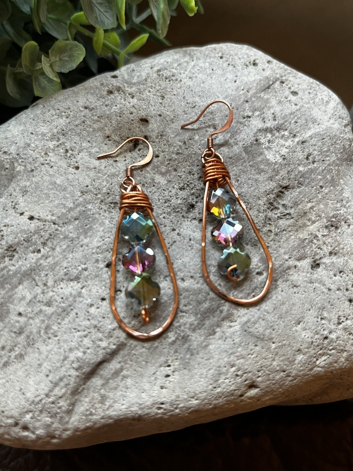 Cowgirl Trading Post handcrafted copper wire teardrop earrings with shimmering multi-faceted beads on a stone surface.