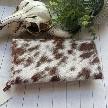 Cowhide pouch on a wooden surface with a skull and plant in the background
