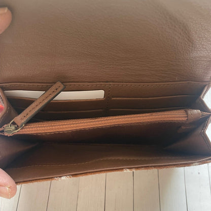 Brown leather wallet held open on a wooden surface