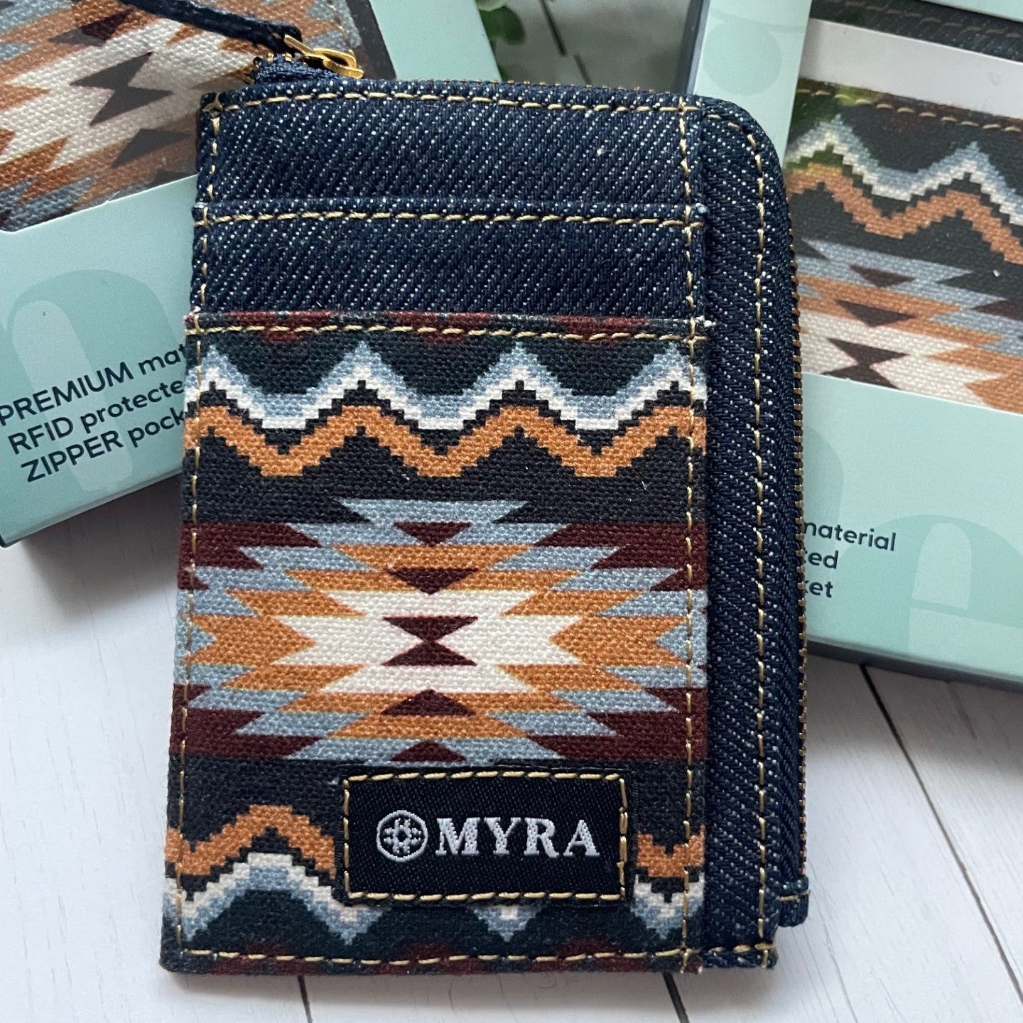 Denim cardholder with geometric pattern and 'MYRA' branding on a white surface.