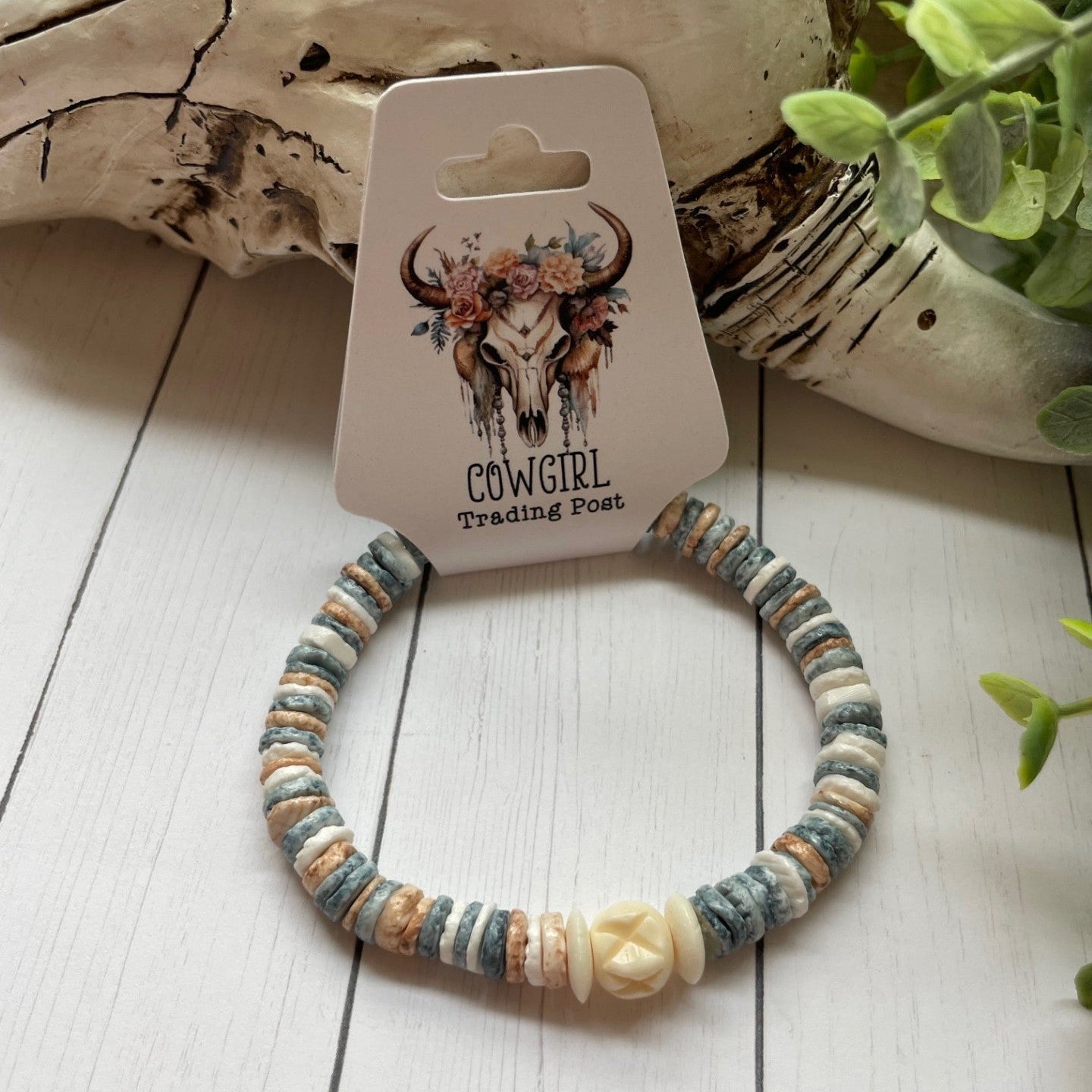 round pastel beads with a white bead accent on a white wooden surface, branded 'The Cowgirl Trading Post'.