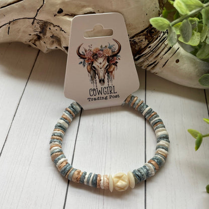 round pastel beads with a white bead accent on a white wooden surface, branded 'The Cowgirl Trading Post'.