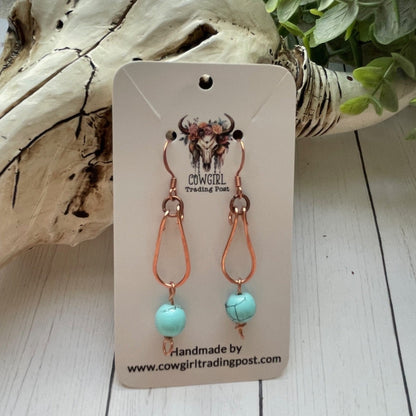 Copper Loop with a Turquoise colored bead hanging from copper colored earrings